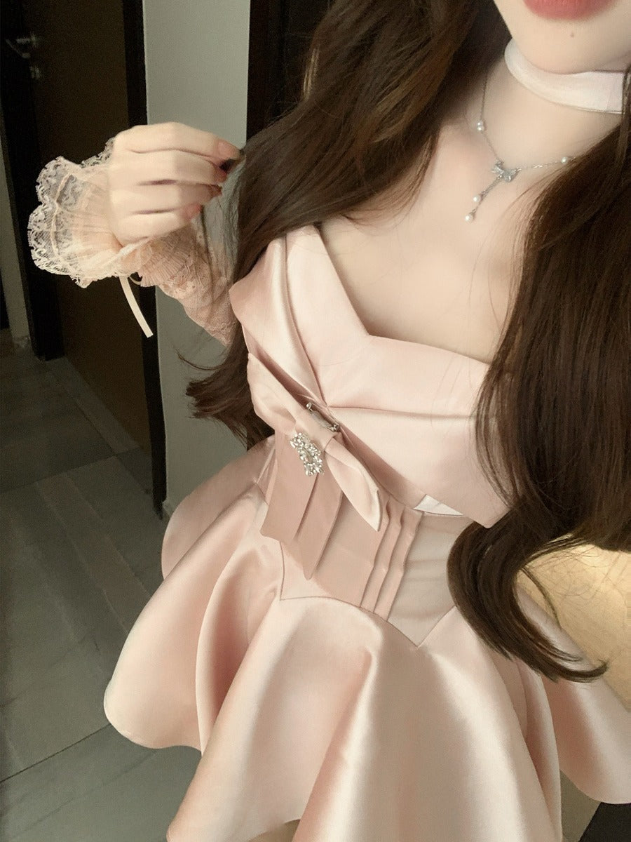 Person wearing a light pink dress with a belt and lace gloves indoors.