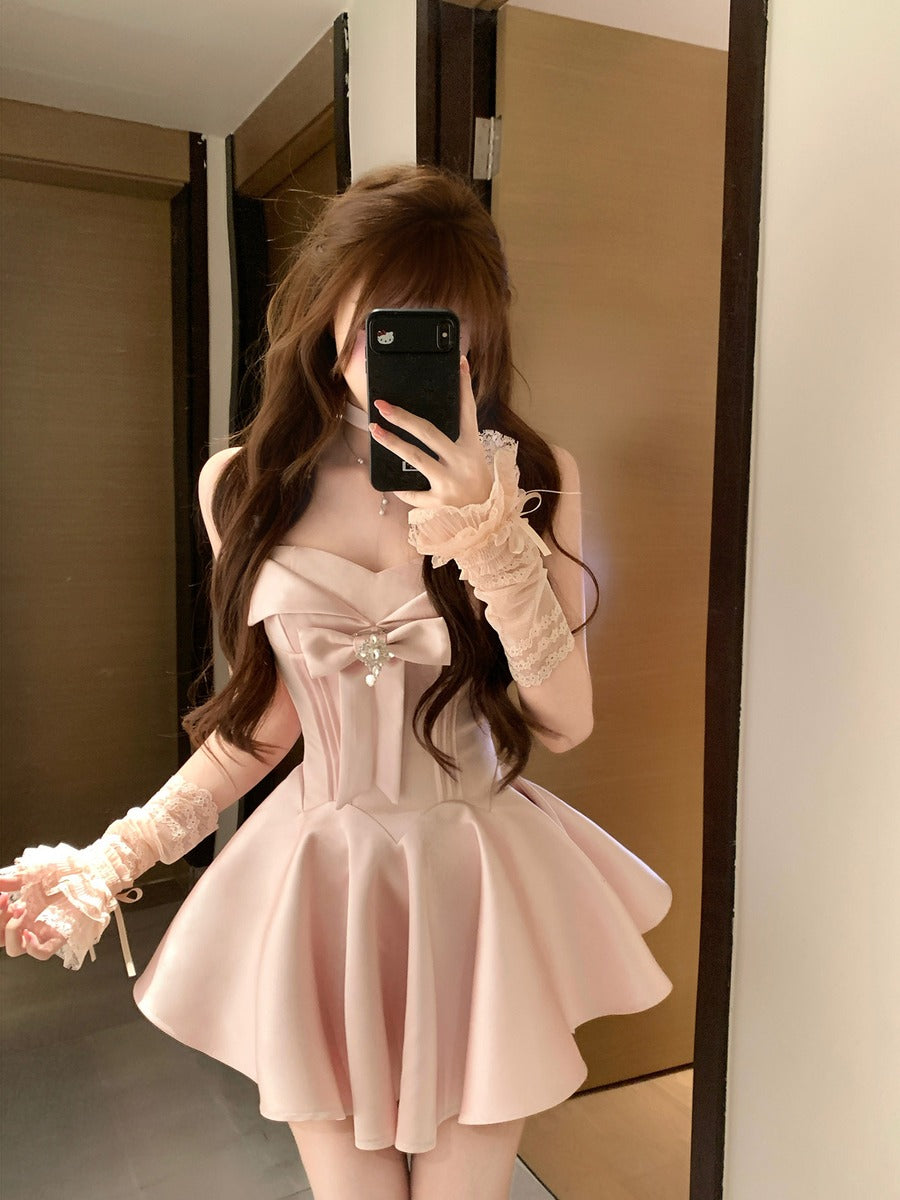 Person wearing a pink dress with a bow and long sleeves in front of a mirror.