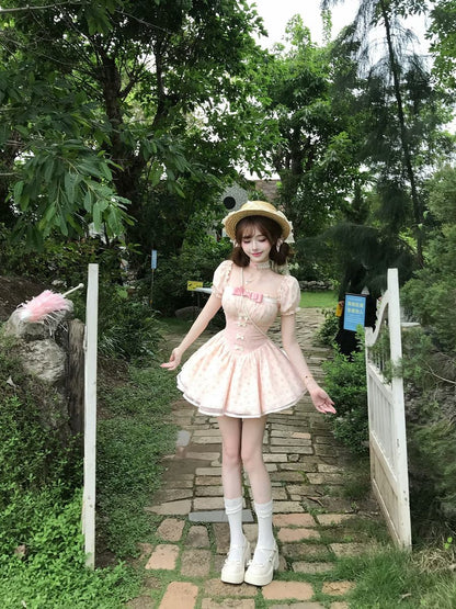 Woman in a pink dress and straw hat standing on a stone path in a forested area.