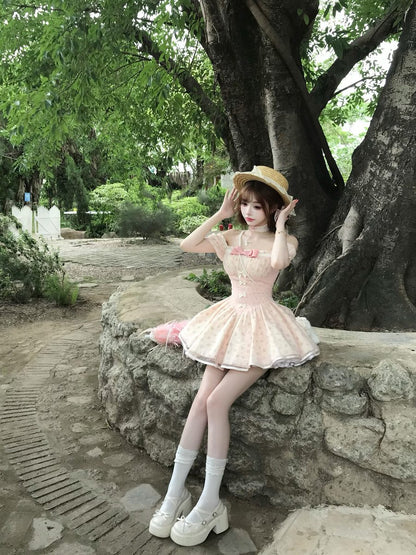 Woman in a pink dress sitting on a stone wall with a large tree in the background