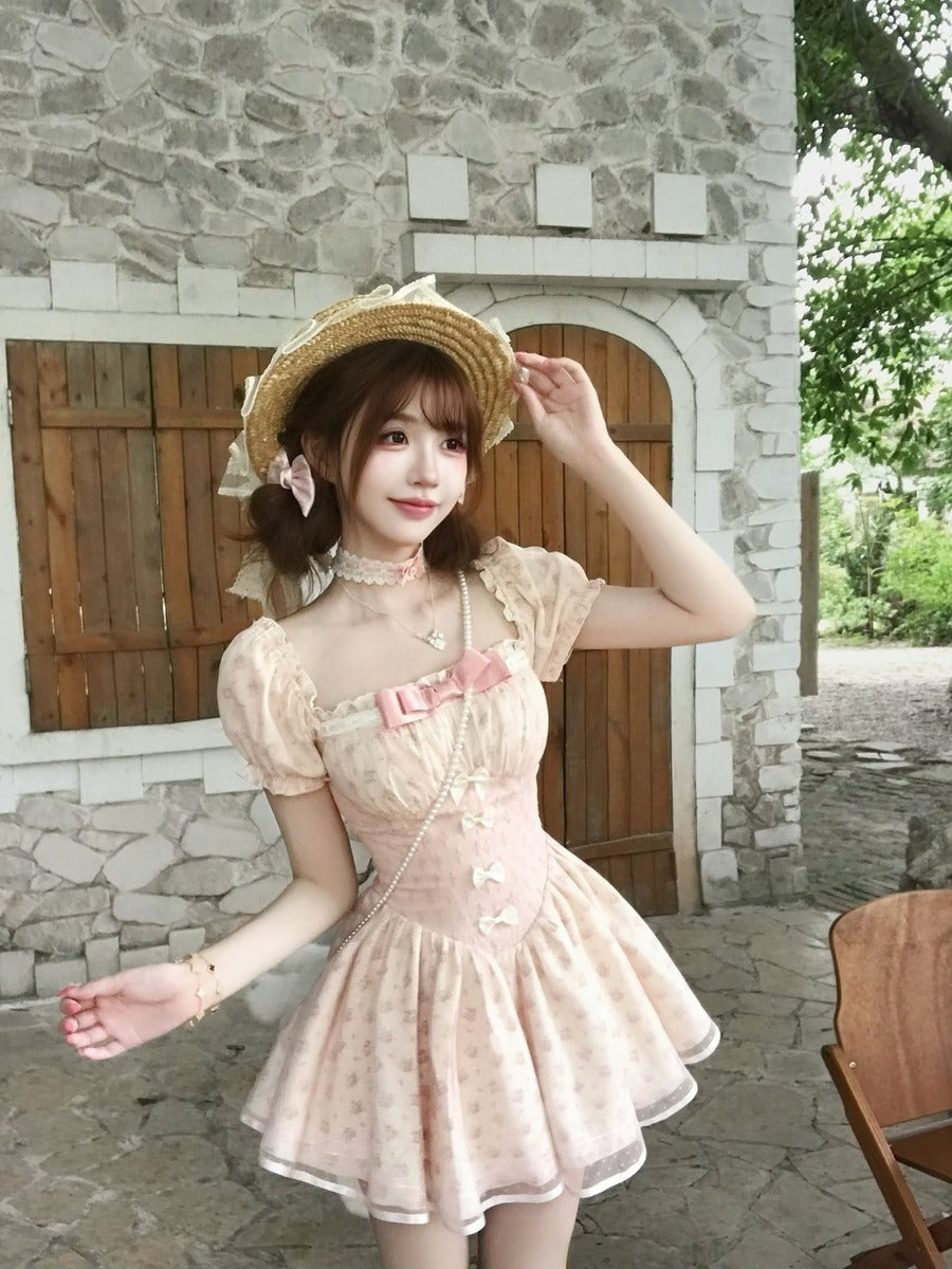 Woman in a pink dress and straw hat standing in front of a stone building.