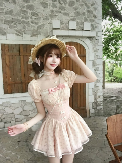 Woman in a pink dress and straw hat standing in front of a stone building.