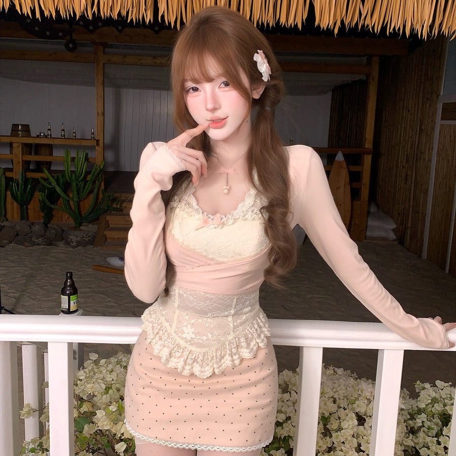 Woman in a light pink dress standing in a decorated indoor setting with plants and a bottle.