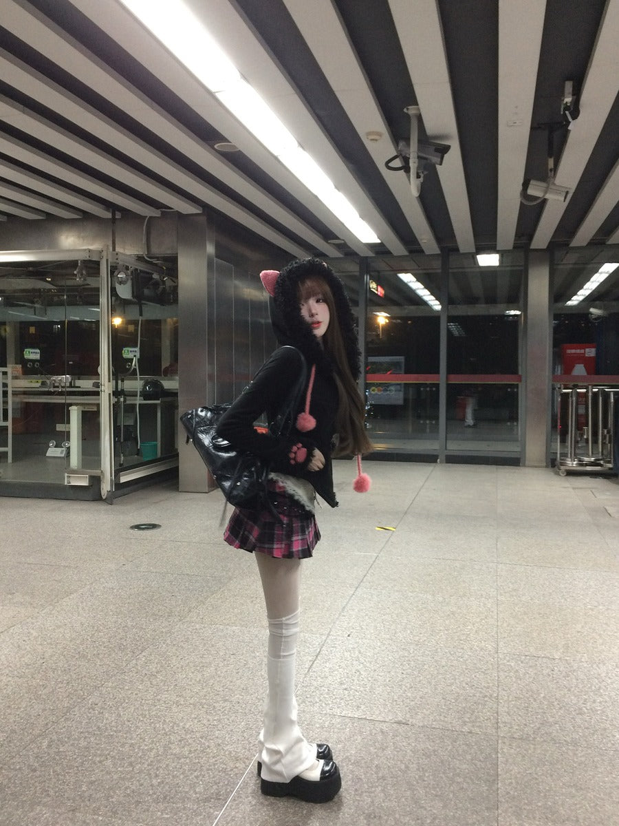 Person wearing a black outfit with a skirt and white stockings in an indoor setting