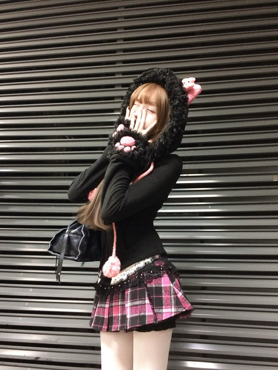 Person wearing a black outfit with pink accents in front of a metallic shutter.