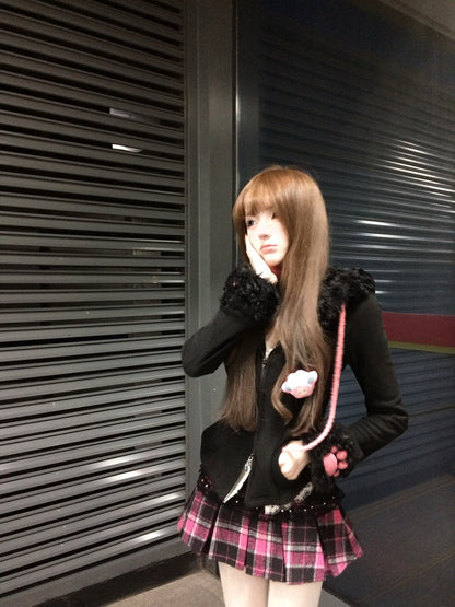 Person wearing a black outfit with fur trim and a pink and white bag, standing against a metallic shutter.