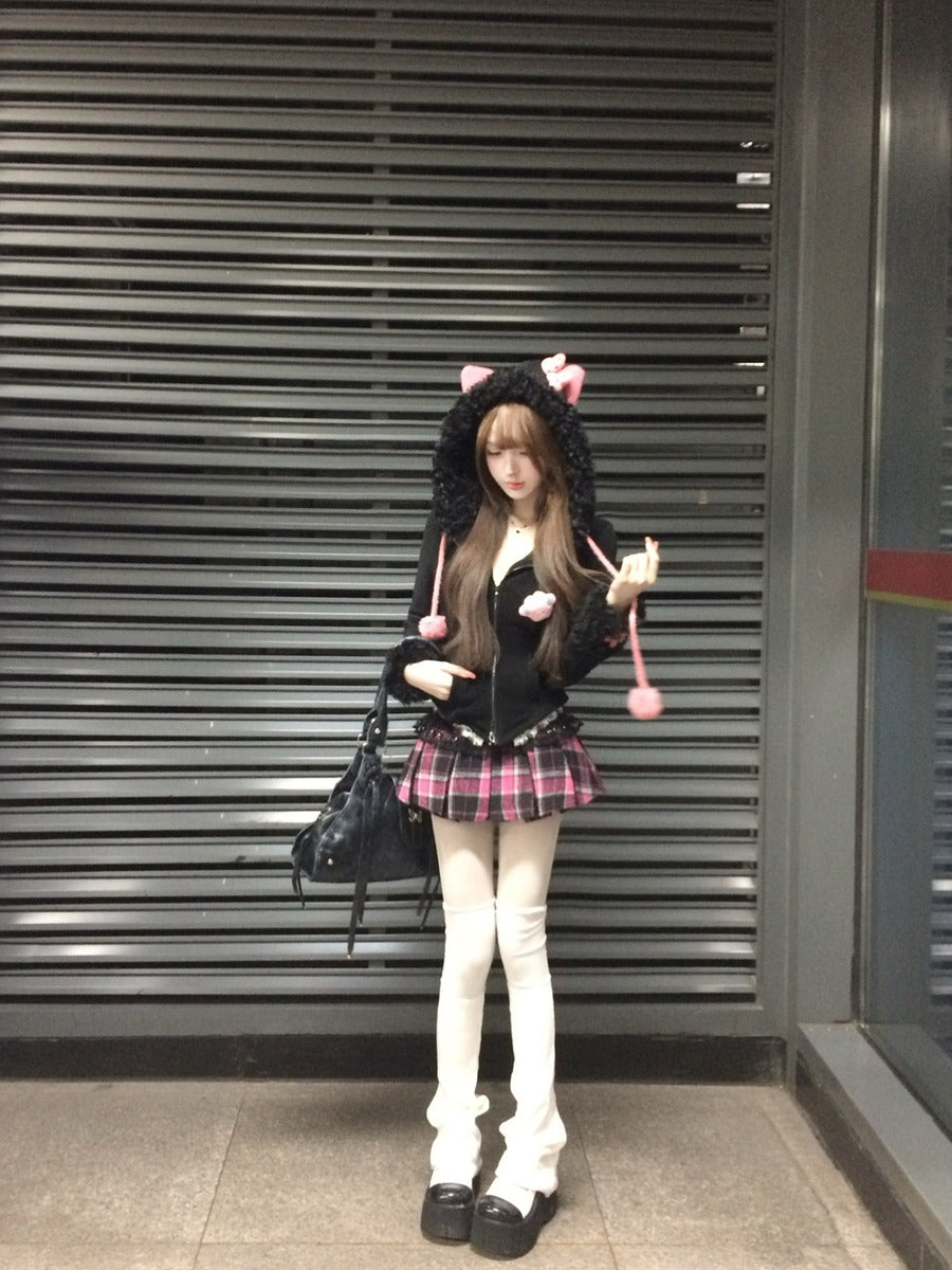 Person wearing a black hoodie with cat ears and a plaid skirt standing in front of a metallic shutter.