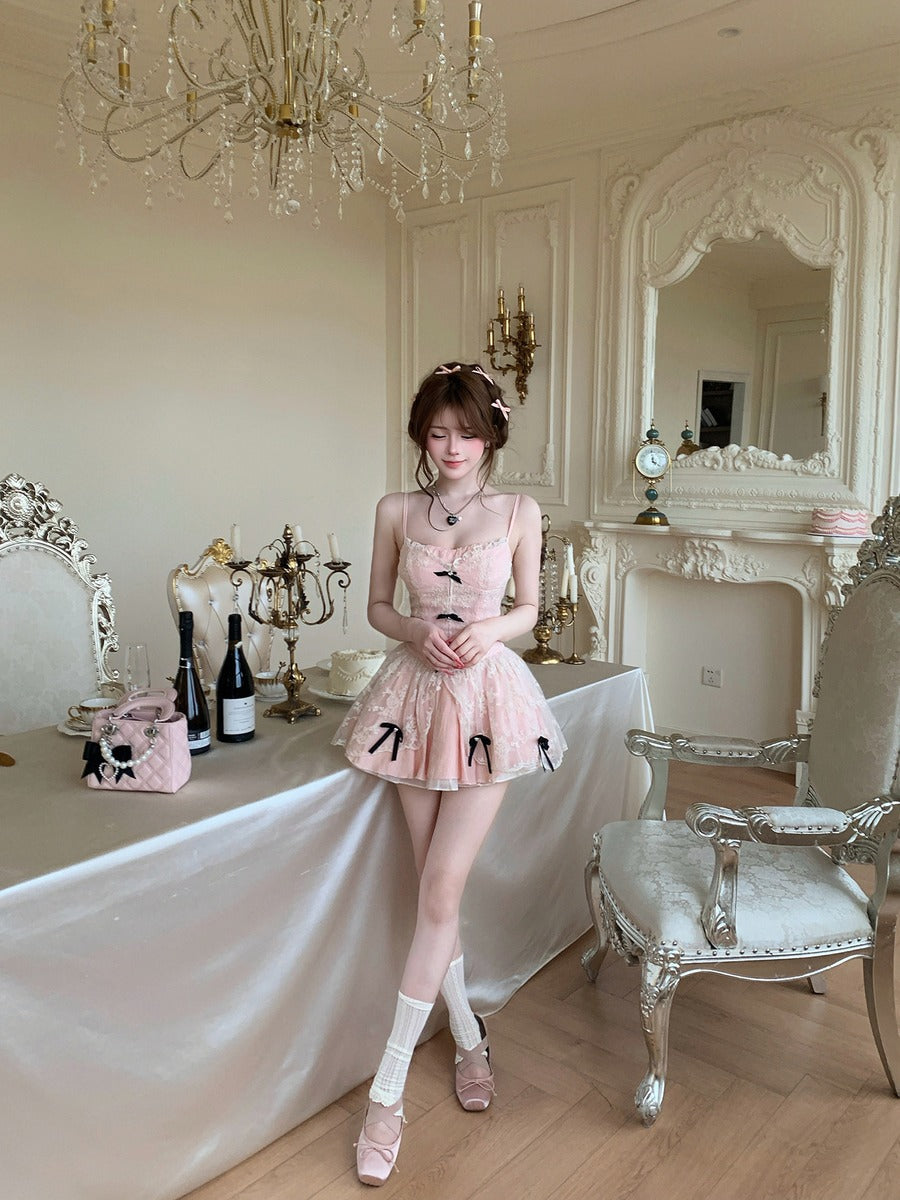Woman in a pink dress standing in an elegant room with chandelier and fireplace.