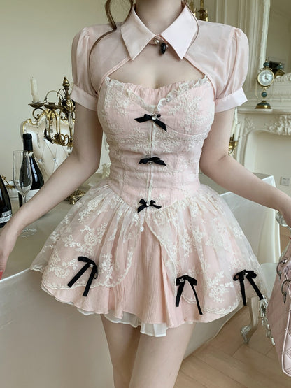 Pink lace dress with black bows on a mannequin in an elegant room setting.
