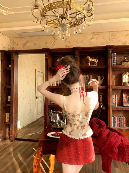 Woman in a floral top and red skirt standing in a room with wooden furniture and decor.
