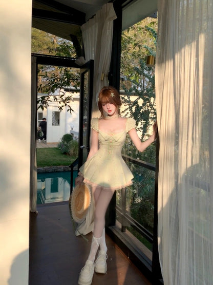Woman in a light green dress standing in a doorway with a garden view.