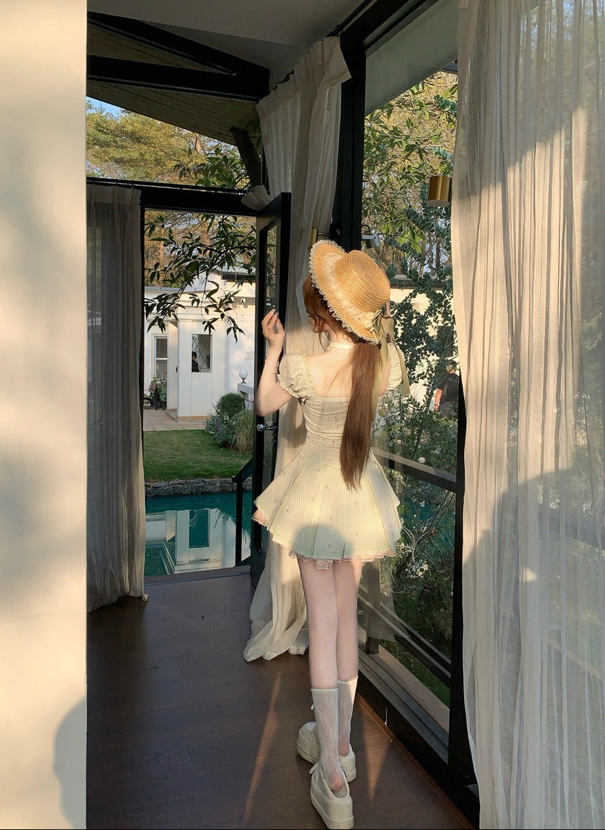 Woman in a green dress and straw hat standing in a doorway with a pool and garden view.