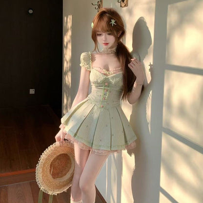 Woman in a light green dress holding a straw hat against a wall with sunlight casting shadows.