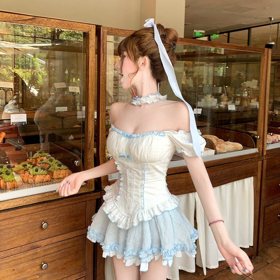 Woman in a maid outfit standing in front of a bakery display case.