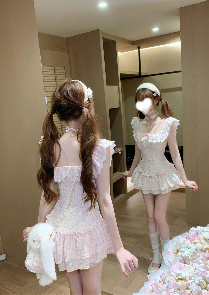 Woman in a white lace dress standing in a room with flowers.