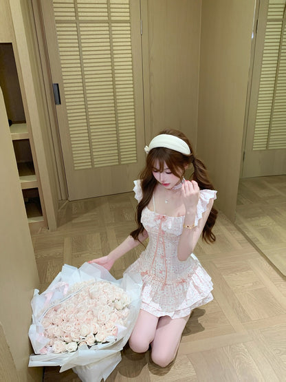 Woman in a white lace outfit holding a large bouquet of flowers in a room with wooden flooring.
