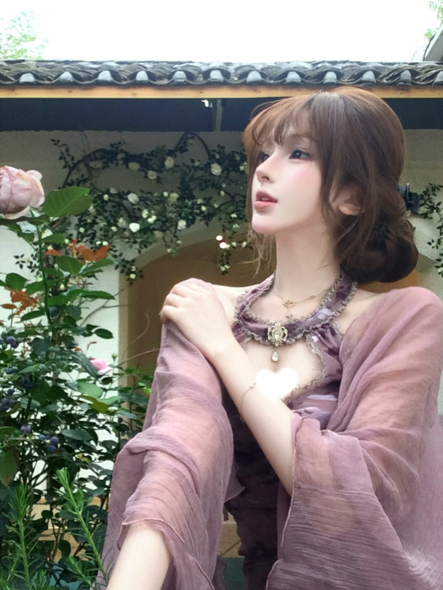 Woman in a pink dress with a necklace, sitting outdoors with plants and flowers in the background