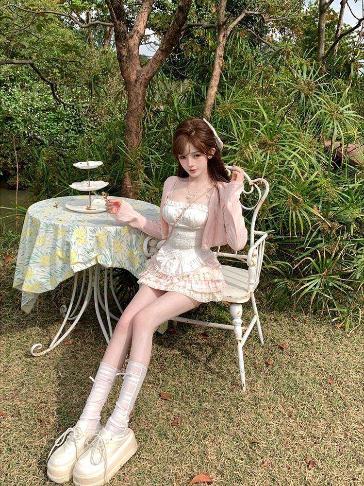 Woman in a garden setting with a table and chairs, wearing a white dress and platform shoes.