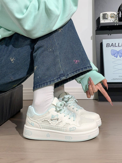 Person wearing white sneakers with floral details, light green sweater, and blue jeans.
