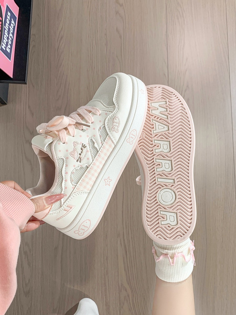 Pink sneaker with floral details on a wooden floor.