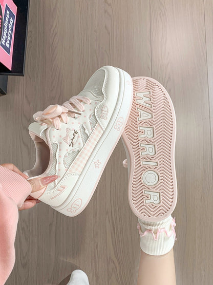 Pink sneaker with floral details on a wooden floor.
