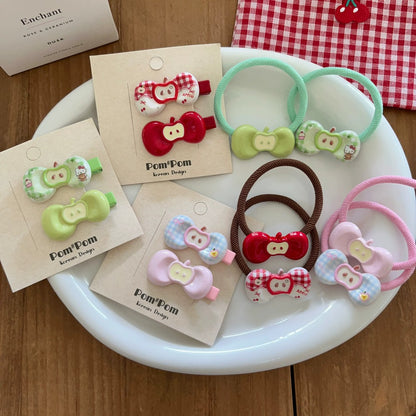Colorful hair ties and clips on a white plate with 'Pom Pom' packaging on a wooden surface.