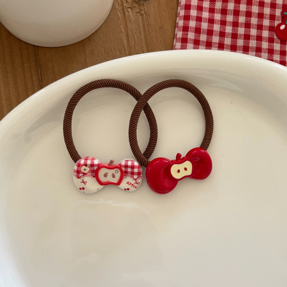Two brown hair ties with red and white cartoon character ends on a white surface.