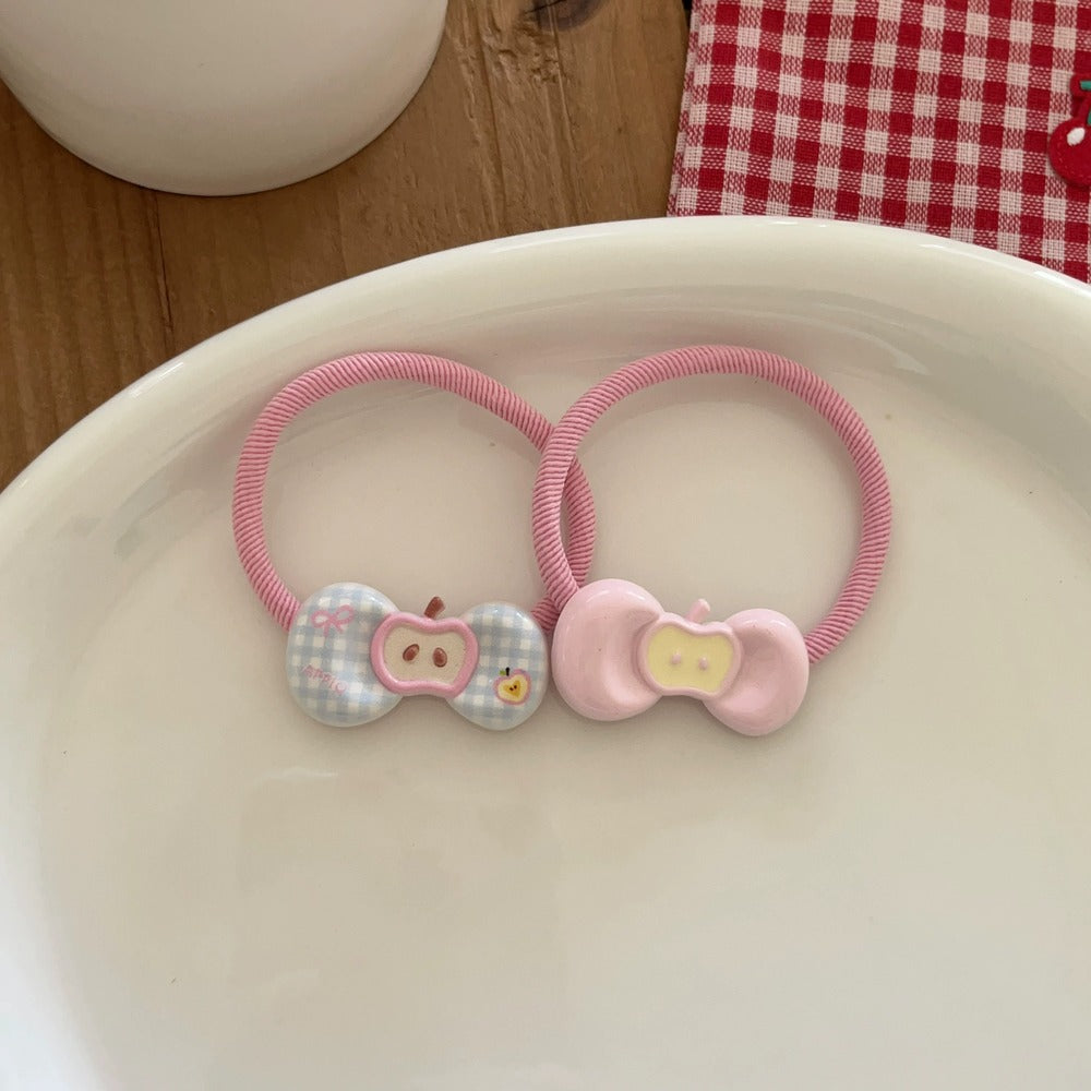 Two pink hair ties with cartoon character ends on a white plate.