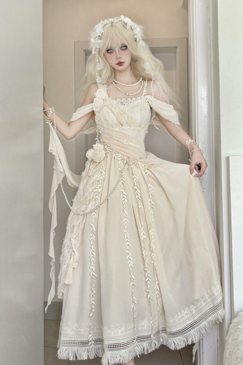 A woman wearing a cream-colored off-the-shoulder Lolita dress with lace details, a matching floral headpiece, and pearl necklaces, posing in front of a neutral indoor background.