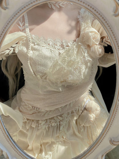 An ivory lace and satin dress with floral appliqués, shown in a close-up reflection inside an ornate oval mirror.