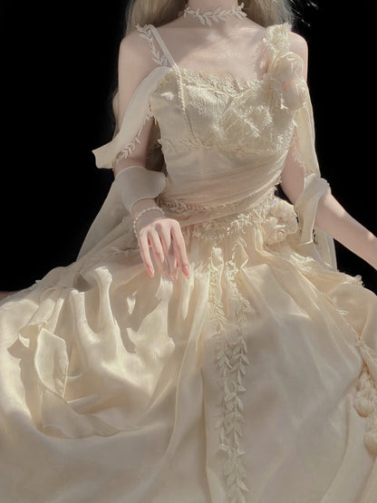 A cream-colored ballgown with intricate lace and floral embroidery, worn by a model against a solid black background.