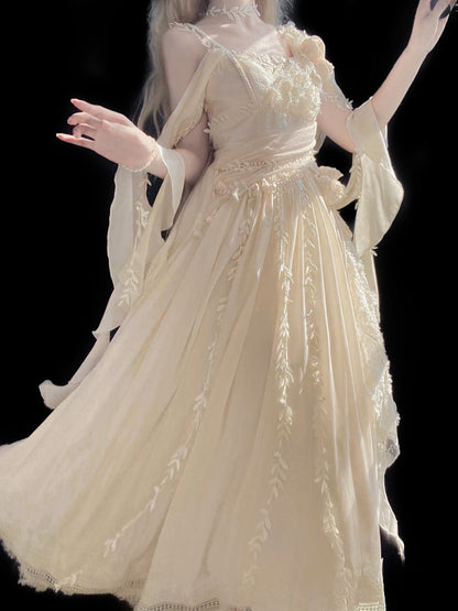 A woman wearing a flowing cream-colored fantasy-style gown with sheer sleeves, floral embroidery, and a voluminous skirt, posed against a solid black background.