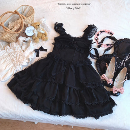 Black lace dress on a white surface with accessories including shoes and a teddy bear.