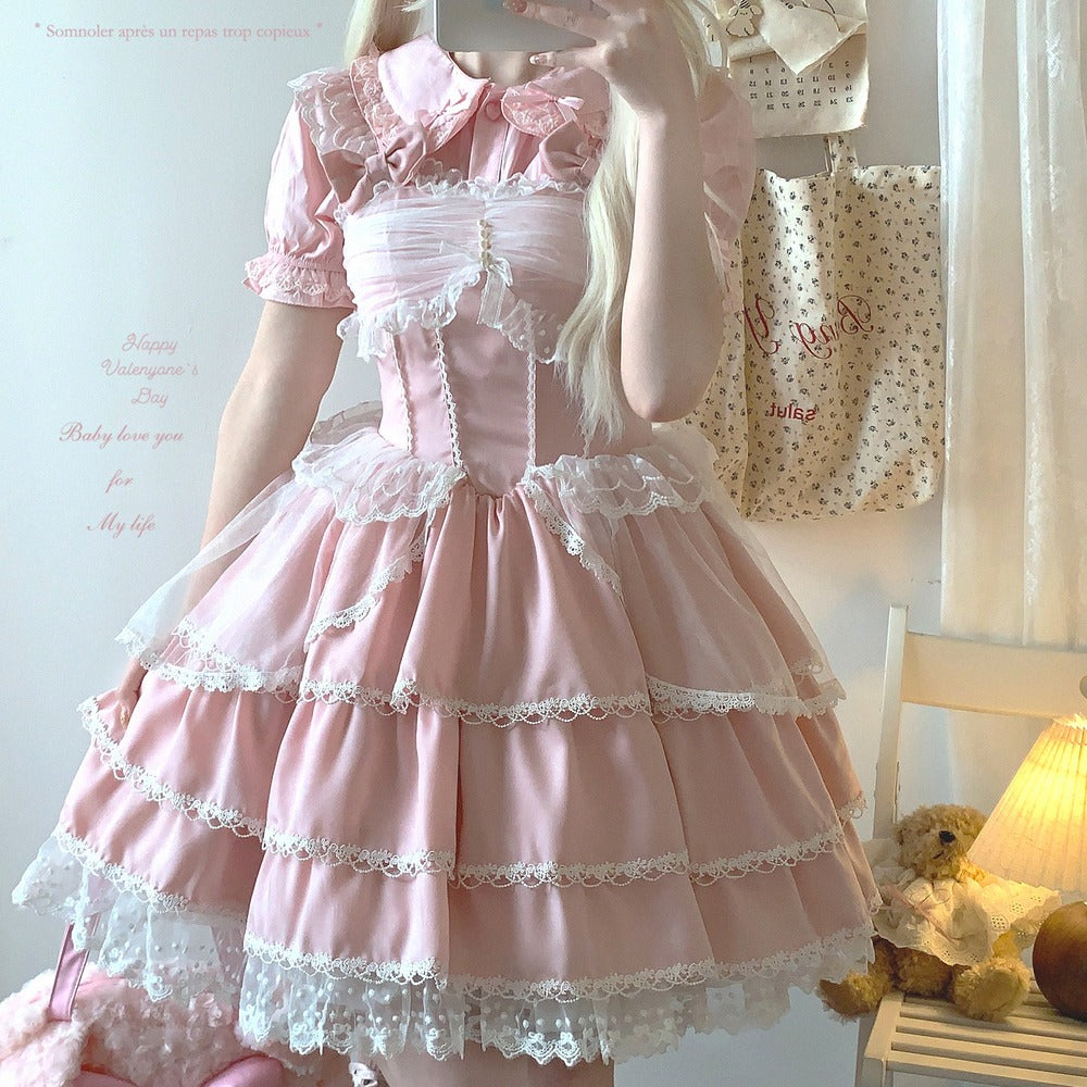 Person wearing a pink lace dress in a room with a teddy bear and lamp.