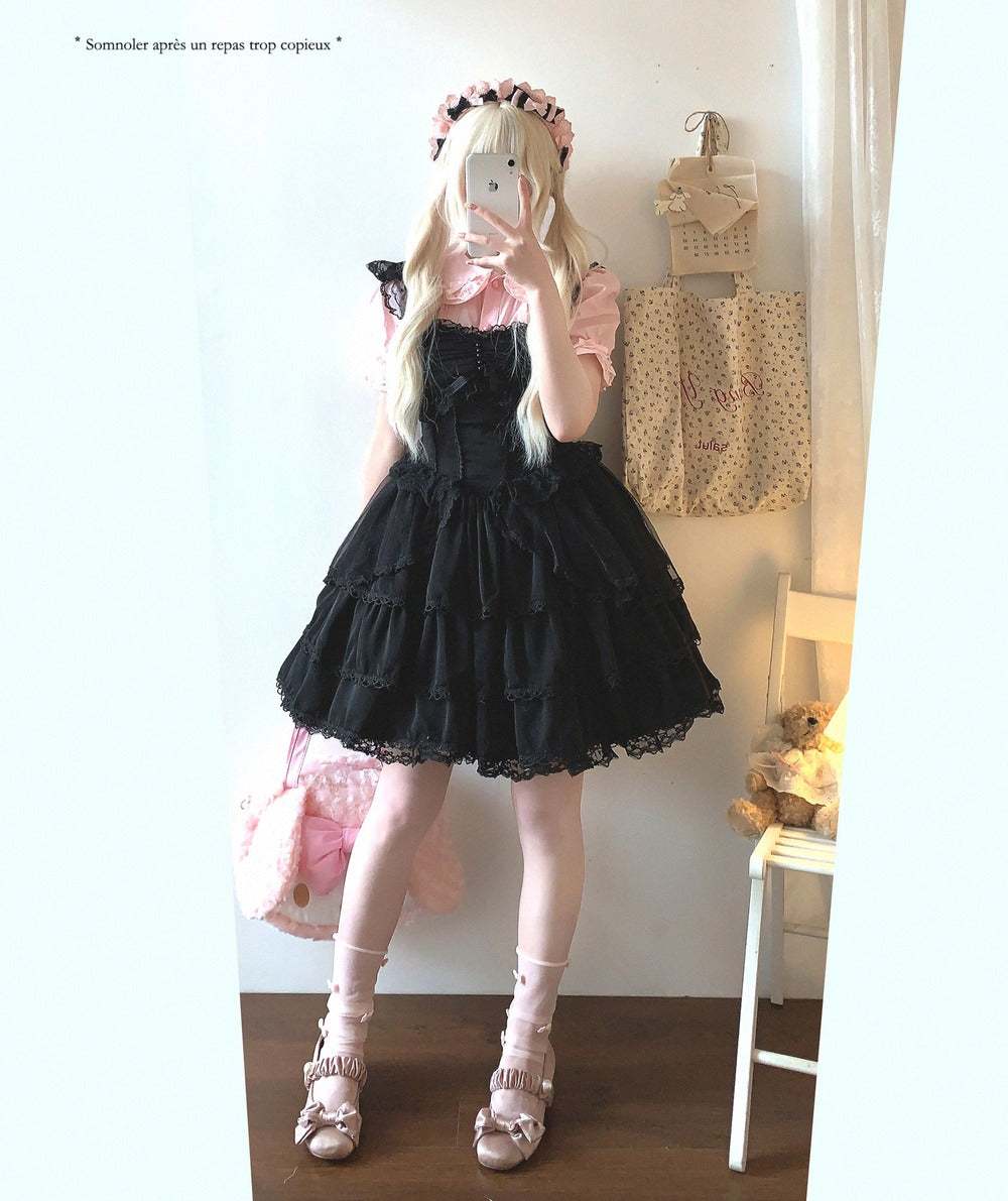 Person wearing a black lace dress with white stockings and shoes, standing in a room.