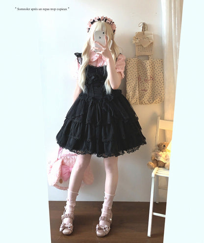 Person wearing a black lace dress with white stockings and shoes, standing in a room.