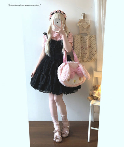 Person in a black and pink outfit with a large pink bag, standing in a room.