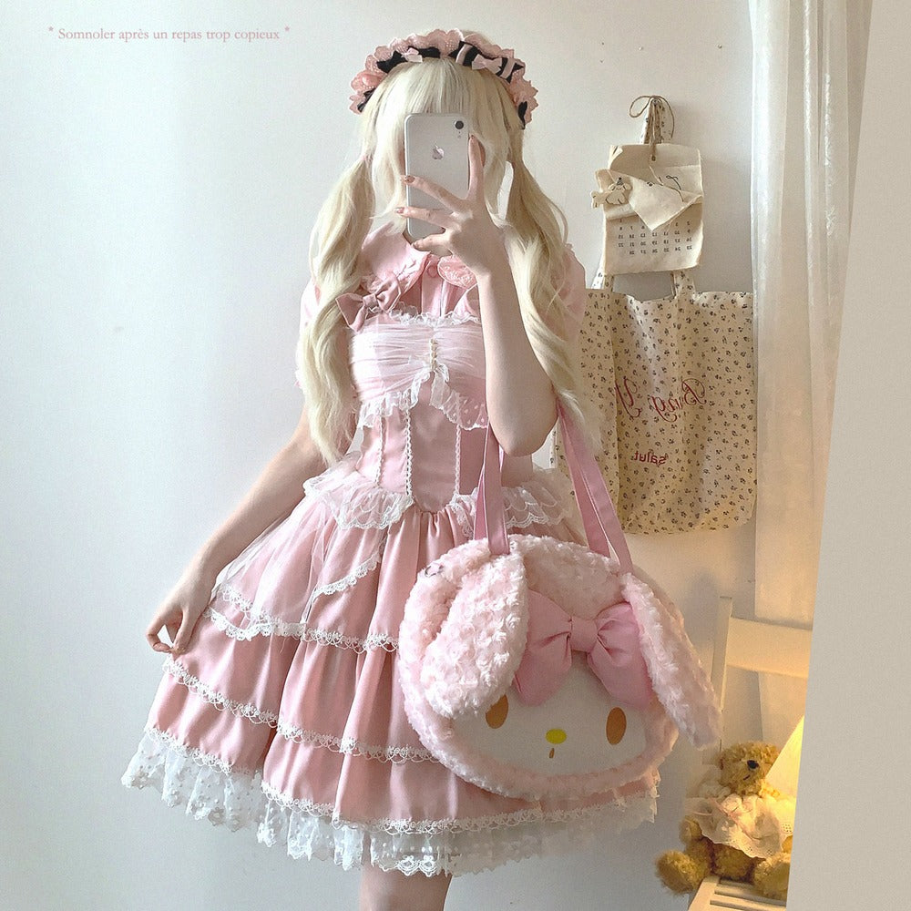 Person wearing a pink dress with a matching bag, taking a mirror selfie.