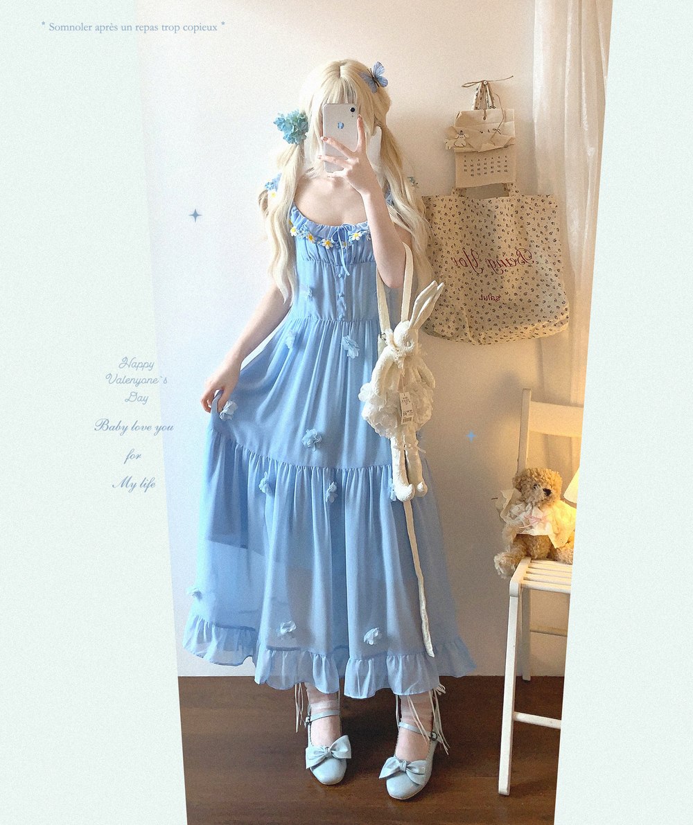 Person wearing a light blue dress with floral details in a room.