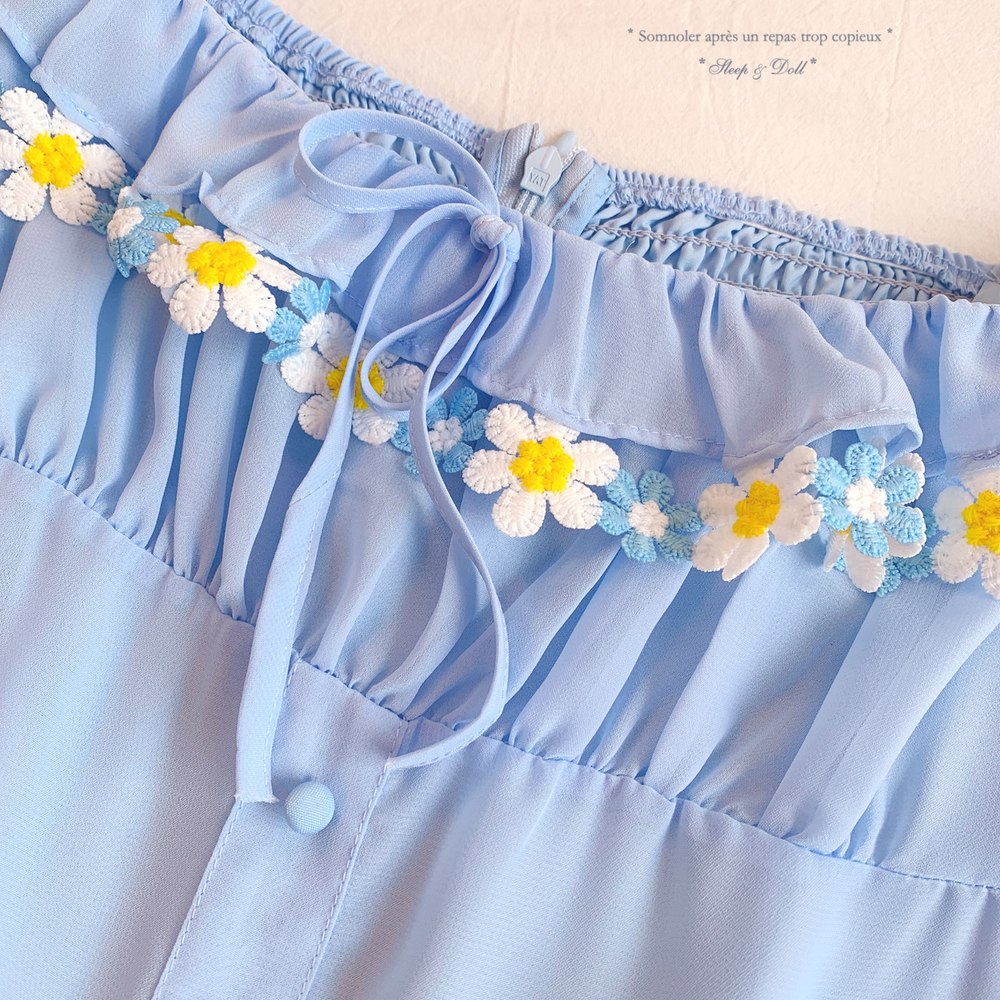 Light blue dress with floral embellishments on a beige background