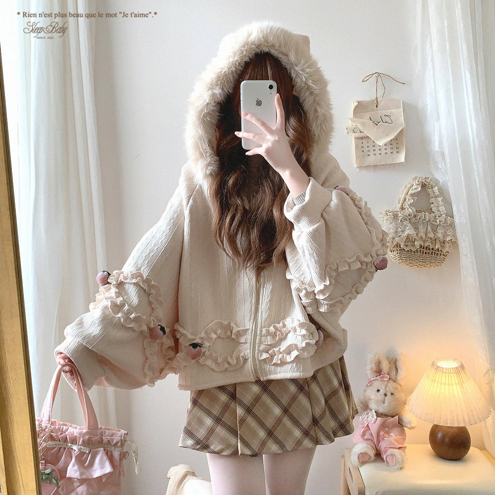 Person wearing a fluffy hooded strawberry jacket and plaid skirt taking a mirror selfie.