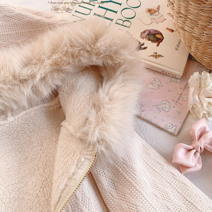 Close-up of a fluffy beige blanket with books and a pink bow in the background