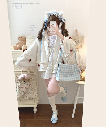 Person in a cute strawberry jacket with a teddy bear and decorative items in the background