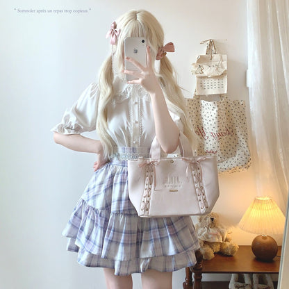 Person in a white blouse and plaid skirt holding a pink handbag with a mirror.