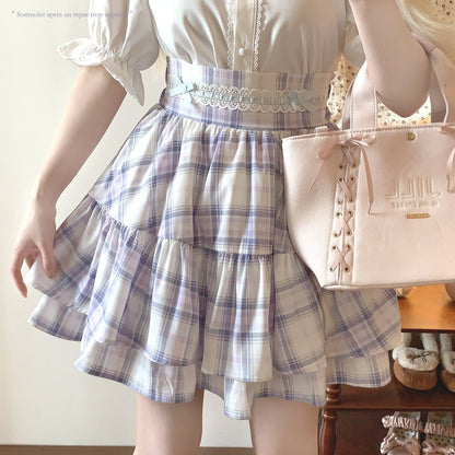 Person wearing a white blouse with a plaid skirt and holding a pink handbag.