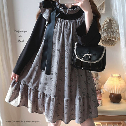 Person wearing a gray dress with black patterns and holding a matching handbag in a softly lit room.