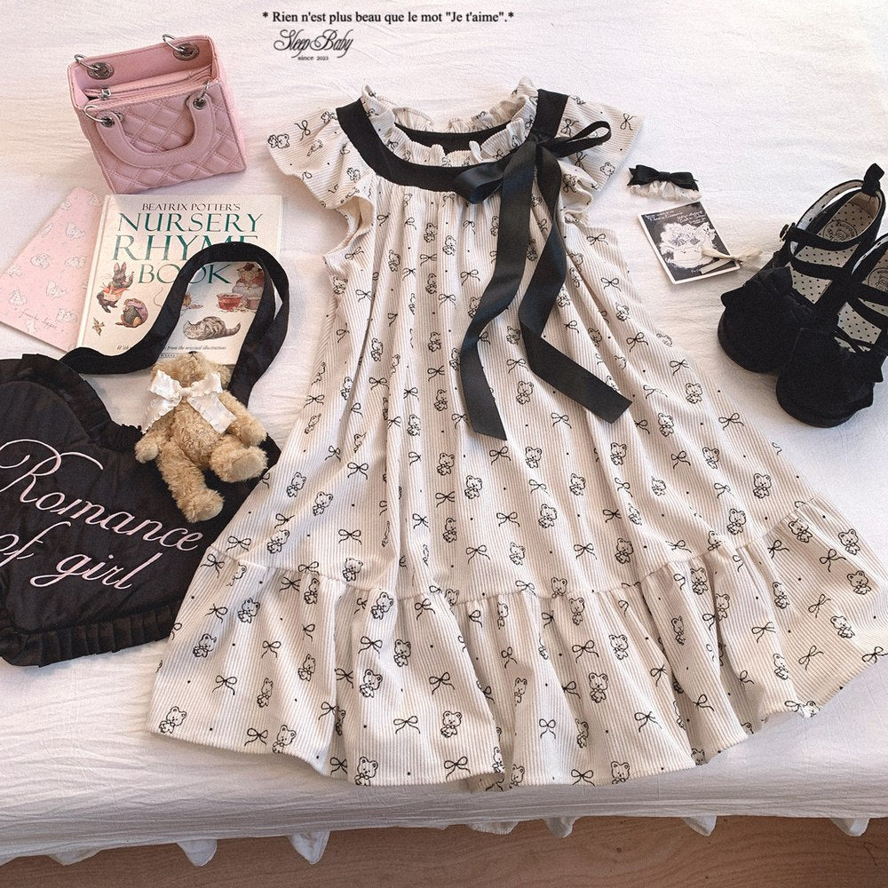 White dress with black ribbon, pink handbag, teddy bear, and books on a white surface