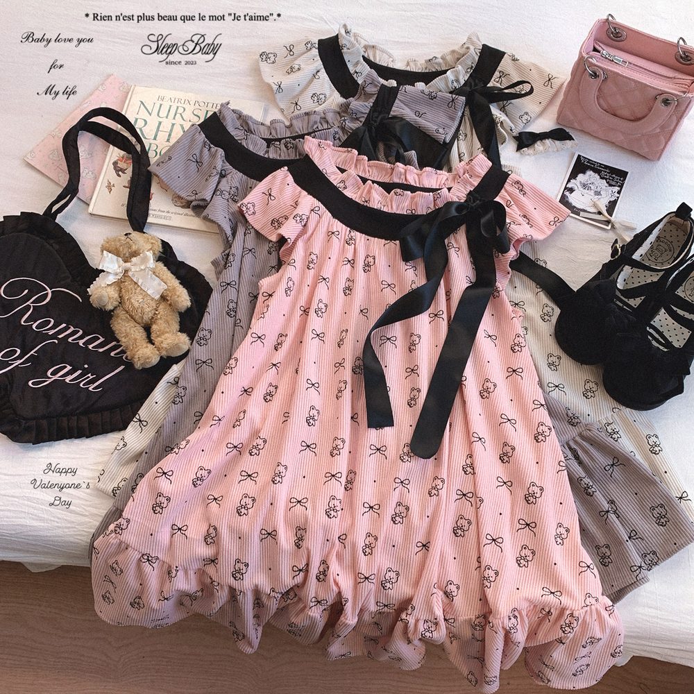 Pink dress with black ribbons on a surface with books and bags