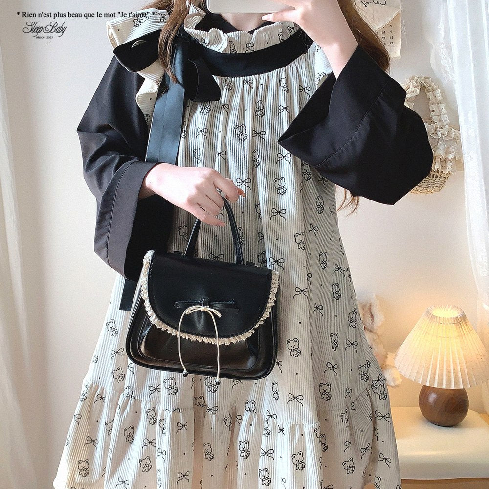 Person holding a black handbag wearing a patterned dress indoors.