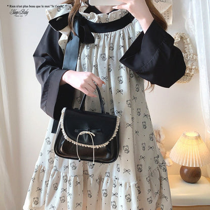 Person holding a black handbag wearing a patterned dress indoors.